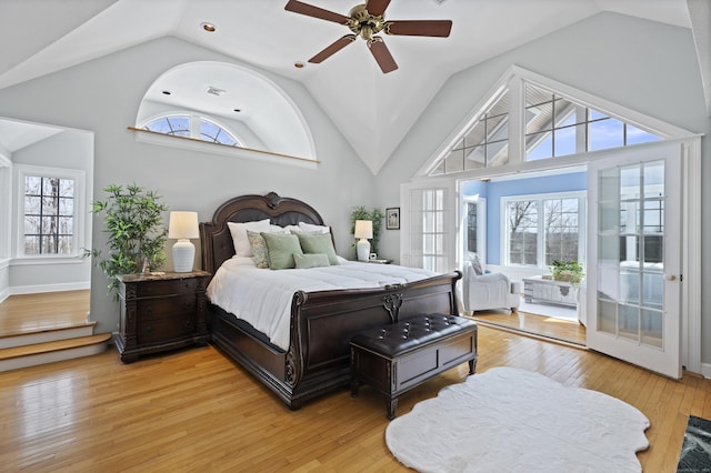 bedroom featuring light wood finished floors, multiple windows, high vaulted ceiling, and a ceiling fan