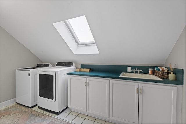 laundry room with cabinet space, a skylight, washer and clothes dryer, a sink, and light tile patterned flooring