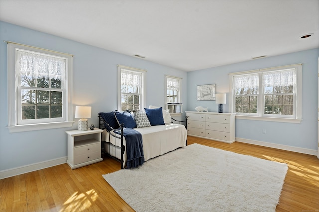 bedroom with light wood-style floors, visible vents, and baseboards