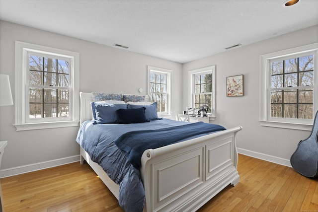 bedroom featuring light wood-type flooring, visible vents, and baseboards