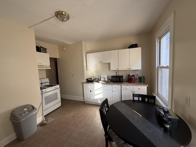 kitchen featuring sink, gas range gas stove, and white cabinets