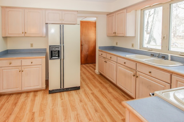 kitchen with light hardwood / wood-style floors, light brown cabinetry, white refrigerator with ice dispenser, and sink