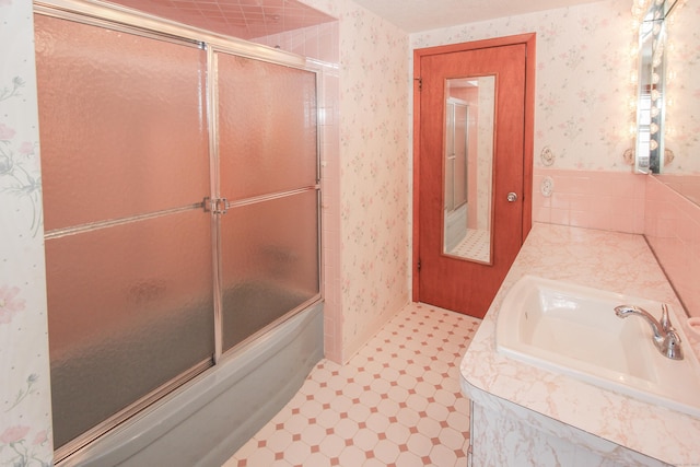 bathroom with shower / bath combination with glass door and sink