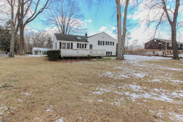 snow covered back of property with a yard and a deck