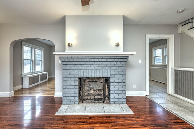 unfurnished living room with dark hardwood / wood-style flooring and a brick fireplace