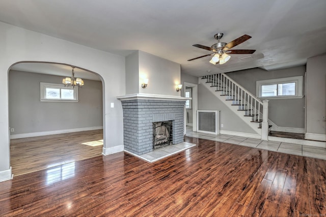 unfurnished living room with hardwood / wood-style flooring, ceiling fan, and a brick fireplace