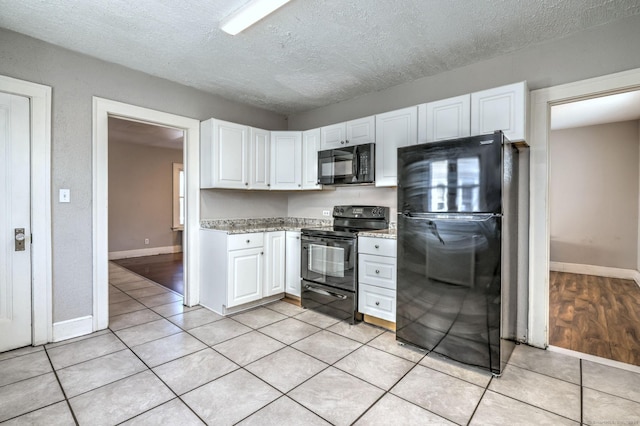 kitchen with white cabinetry, light tile patterned floors, a textured ceiling, and black appliances