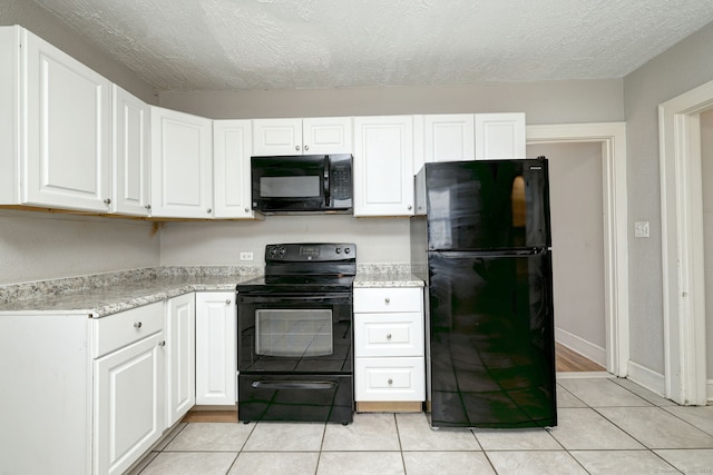 kitchen with light tile patterned flooring, white cabinets, a textured ceiling, and black appliances