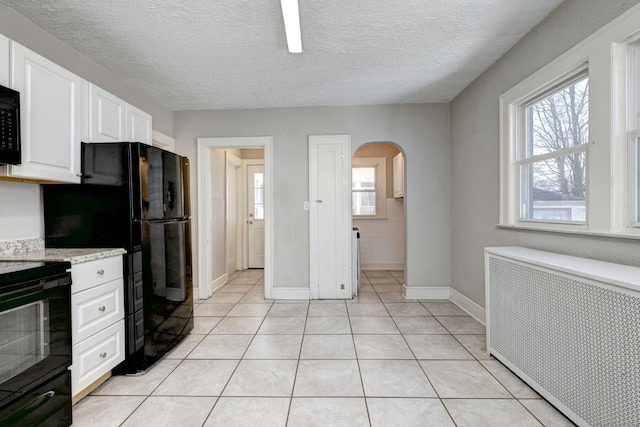 kitchen with radiator, white cabinetry, light tile patterned floors, black range with electric cooktop, and a textured ceiling