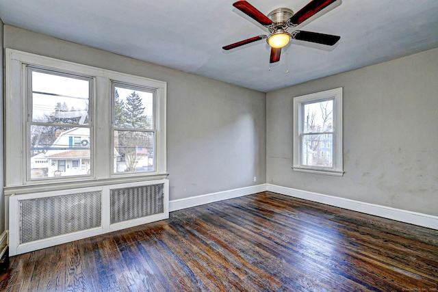 spare room featuring ceiling fan, radiator heating unit, and dark hardwood / wood-style flooring