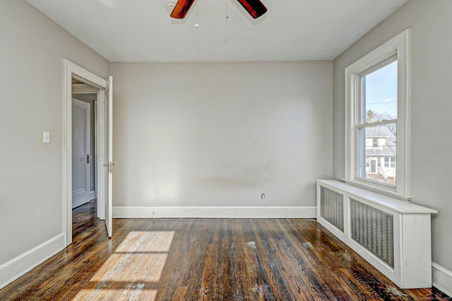 empty room featuring dark wood-type flooring, radiator heating unit, and ceiling fan