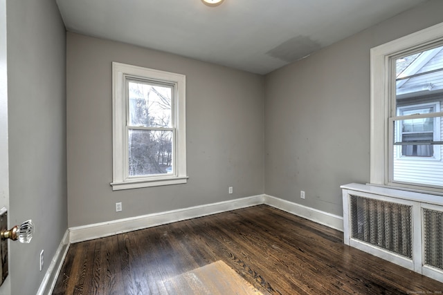 empty room featuring dark hardwood / wood-style flooring and radiator heating unit