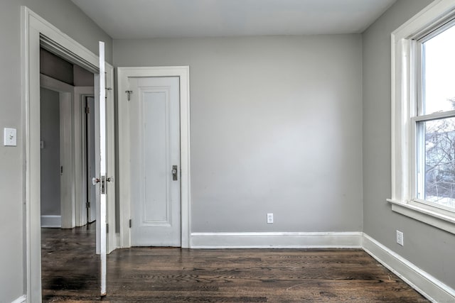 empty room with dark hardwood / wood-style flooring and a wealth of natural light