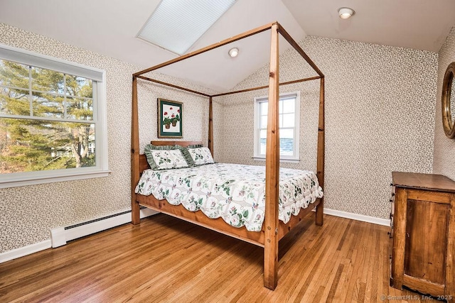 bedroom featuring hardwood / wood-style flooring, lofted ceiling, and a baseboard heating unit