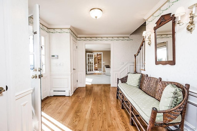 foyer with a baseboard heating unit, crown molding, and light wood-type flooring