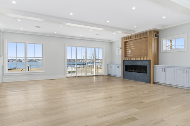 unfurnished living room featuring a fireplace, light wood-type flooring, beamed ceiling, and a water view