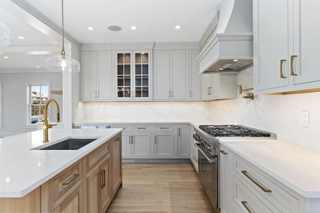 kitchen with sink, a center island with sink, high end stainless steel range, and premium range hood