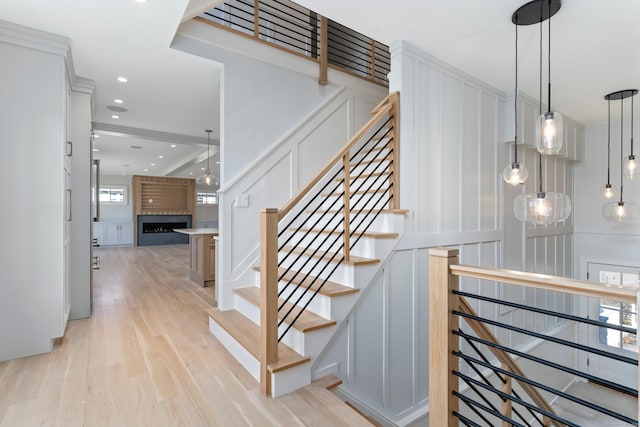 stairway with a large fireplace, wood finished floors, and a decorative wall