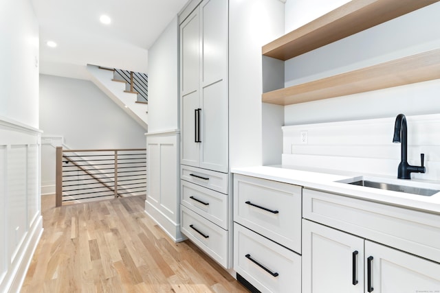 interior space with sink, light hardwood / wood-style flooring, and white cabinets