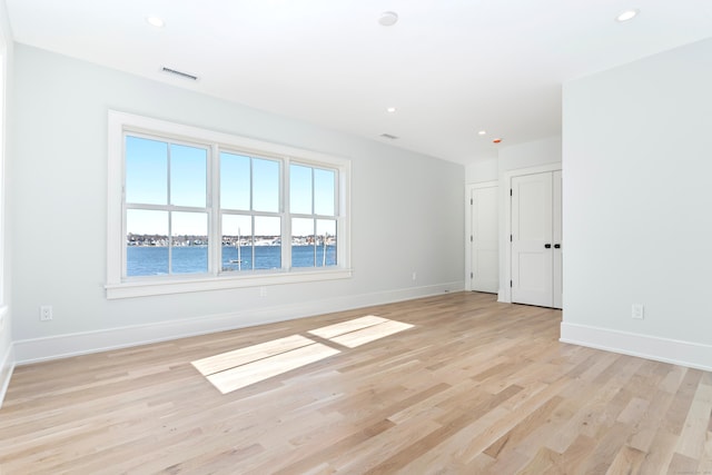 spare room with a water view and light hardwood / wood-style flooring