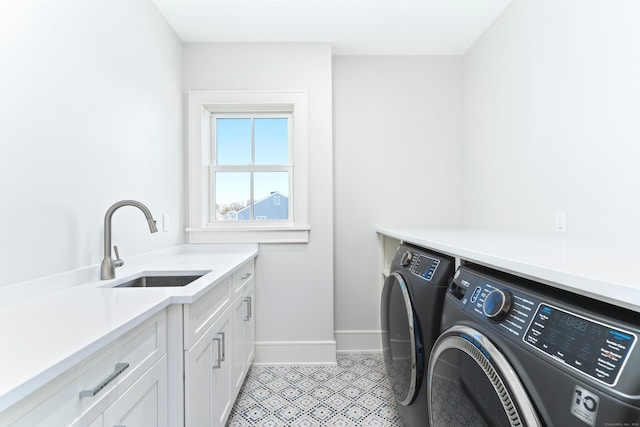 clothes washing area featuring sink, washing machine and dryer, and cabinets