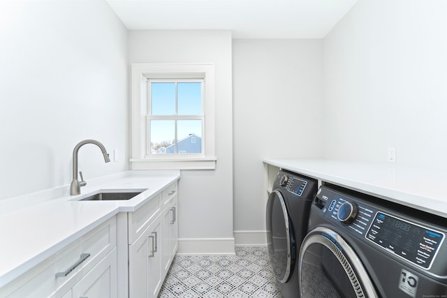 clothes washing area featuring baseboards, a sink, cabinet space, and independent washer and dryer