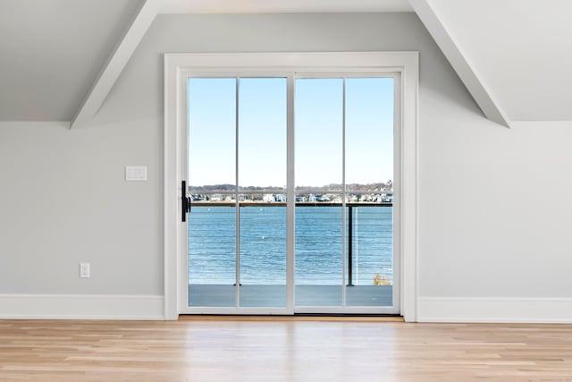 interior space with vaulted ceiling, a water view, and light wood-type flooring