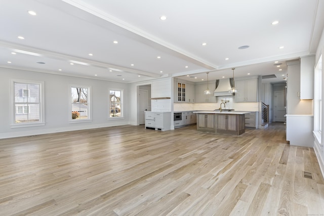 interior space featuring visible vents, a sink, baseboards, light wood finished floors, and ornamental molding