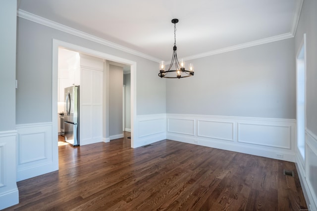 empty room with dark wood-type flooring, crown molding, and an inviting chandelier