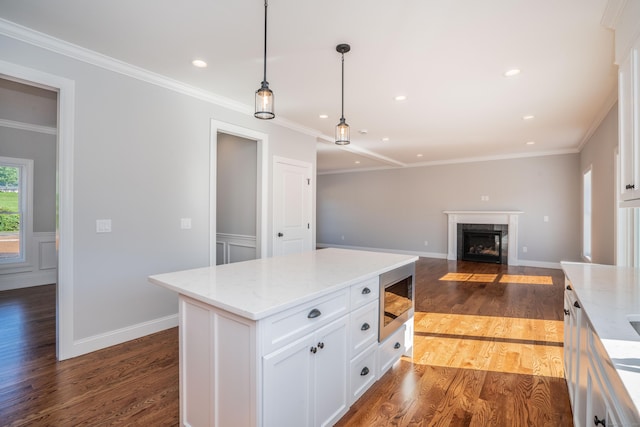 kitchen with white cabinetry, light stone counters, decorative light fixtures, dark hardwood / wood-style floors, and a kitchen island