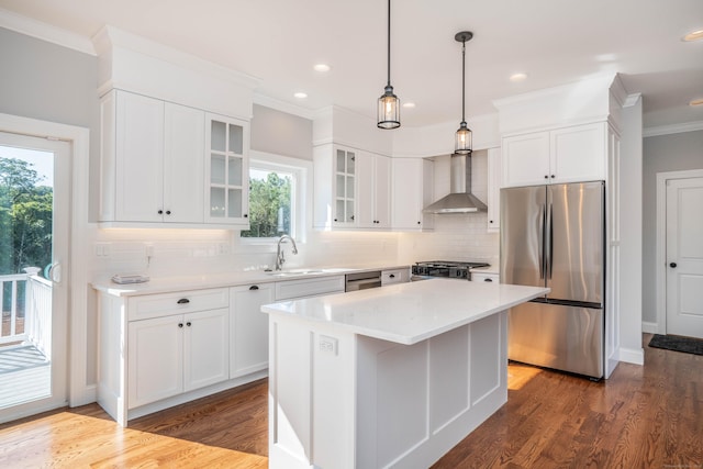 kitchen featuring wall chimney range hood, sink, dark wood-type flooring, stainless steel appliances, and a kitchen island