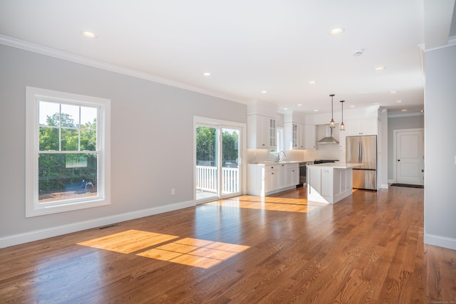 unfurnished living room featuring crown molding, plenty of natural light, sink, and light wood-type flooring