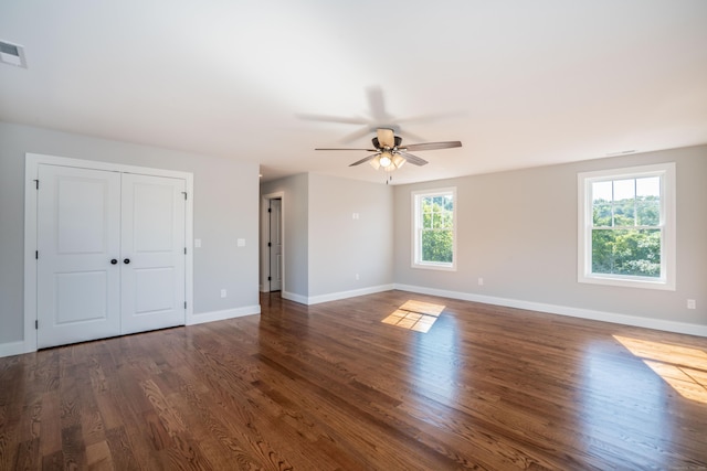 unfurnished room featuring a healthy amount of sunlight, dark wood-type flooring, and ceiling fan