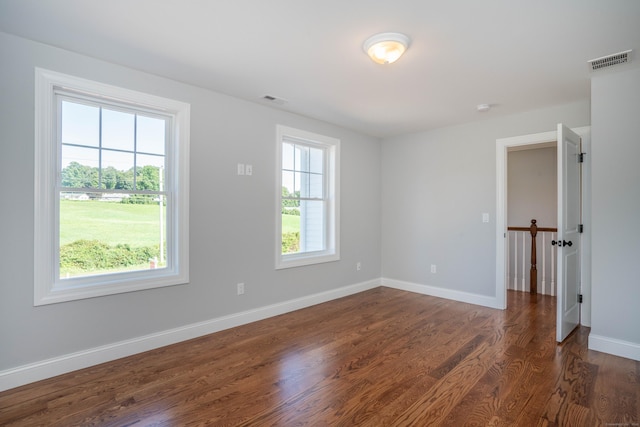 spare room with a healthy amount of sunlight and dark hardwood / wood-style flooring