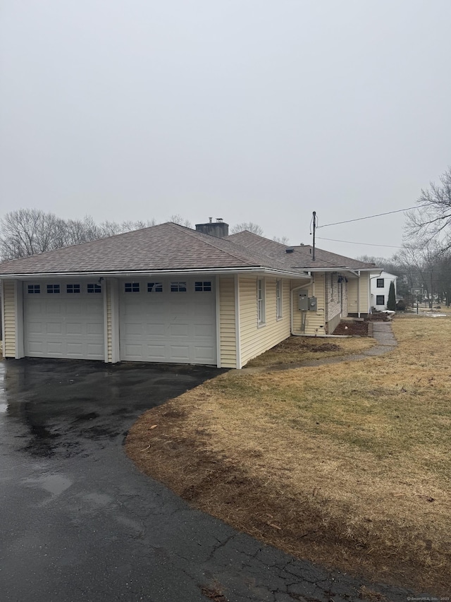 ranch-style house featuring roof with shingles and a front lawn