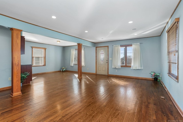 unfurnished living room with decorative columns, baseboards, and wood finished floors