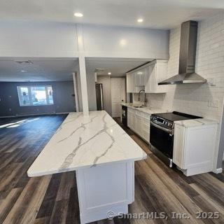 kitchen with sink, white cabinetry, backsplash, stainless steel electric range oven, and wall chimney exhaust hood