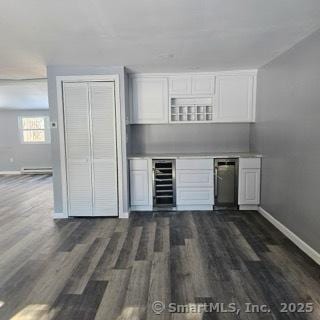 bar with dark wood-type flooring, a baseboard radiator, beverage cooler, and white cabinets