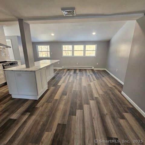 interior space with a baseboard heating unit and dark hardwood / wood-style floors