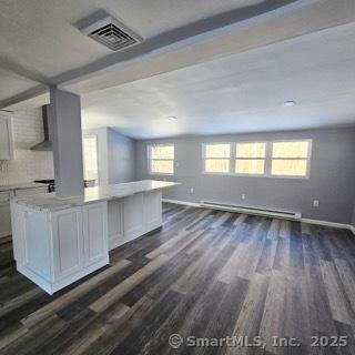 kitchen with baseboard heating, white cabinetry, dark hardwood / wood-style floors, and a center island