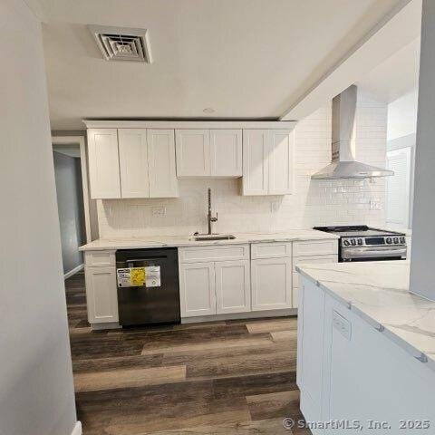 kitchen with sink, stainless steel range, black dishwasher, wall chimney range hood, and white cabinets