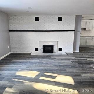 unfurnished living room with dark wood-type flooring and a fireplace