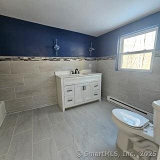 bathroom featuring tile walls, a baseboard heating unit, tile patterned flooring, vanity, and toilet