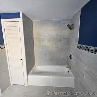 bathroom featuring tile patterned flooring and tiled shower / bath