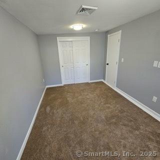 unfurnished bedroom featuring dark colored carpet and a closet