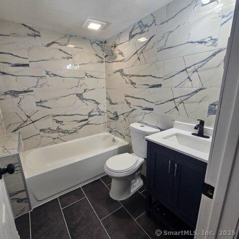 full bathroom with tile patterned floors, toilet, tile walls, vanity, and tiled shower / bath combo