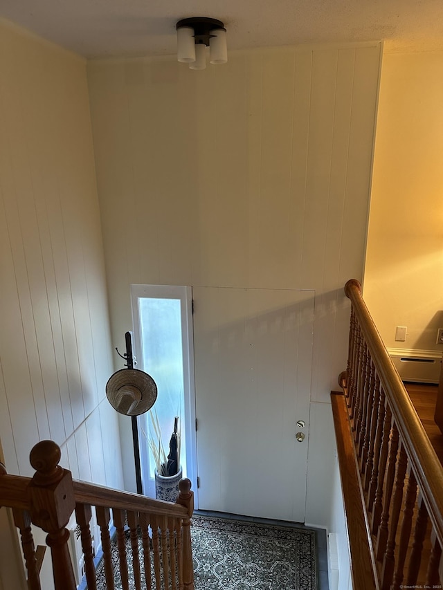 stairs featuring a baseboard radiator and wooden walls