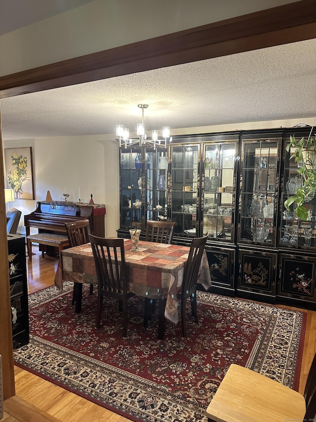 dining space with a notable chandelier, wood-type flooring, and a textured ceiling