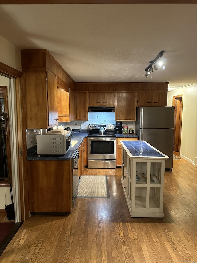 kitchen with decorative backsplash, light hardwood / wood-style flooring, and appliances with stainless steel finishes