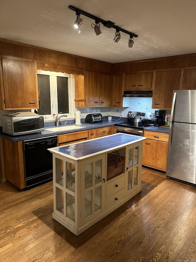 kitchen featuring stainless steel appliances, hardwood / wood-style flooring, sink, and backsplash